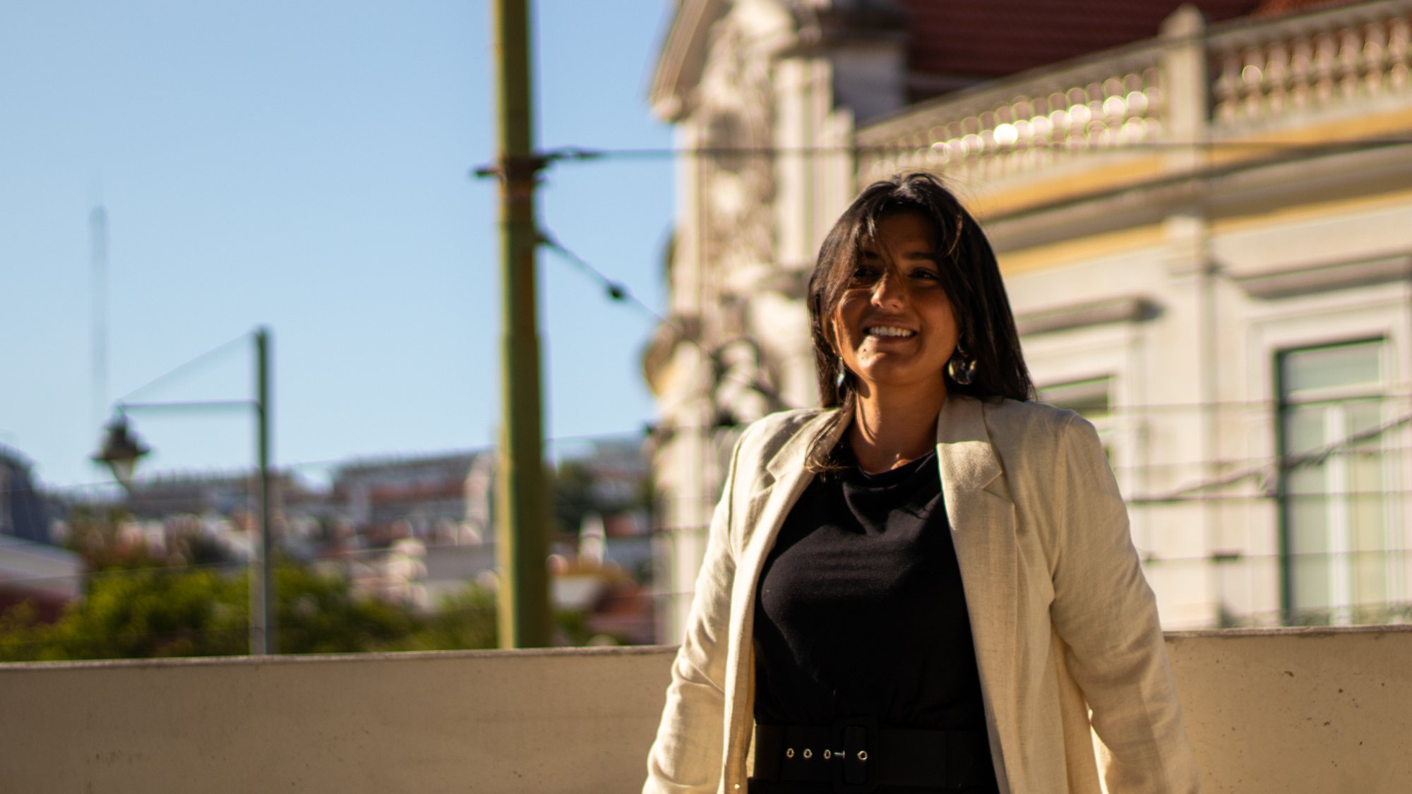 Carol Ferreira, fundadora da Move, em pé numa varanda com a cidade ao fundo